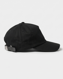 Black cotton baseball cap, front three-quarter view
Black unstructured cap, side profile with leather strap
Black cap rear view with brushed-silver adjustable clasp
Black-on-black embroidered oval logo on cap front